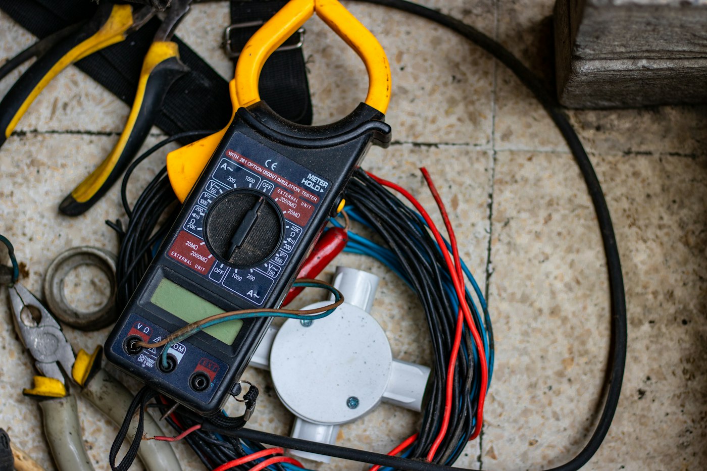 Digital clamp meter resting on coloured electrical cables ready for circuit testing