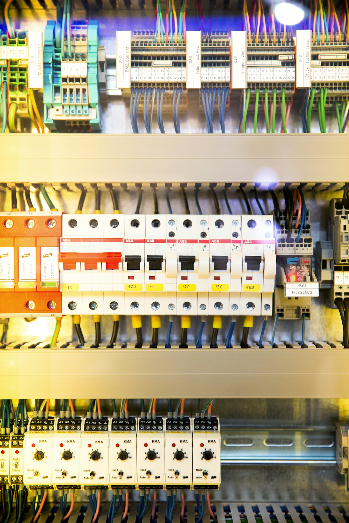 Open distribution box with rows of circuit breakers and colour-coded wiring