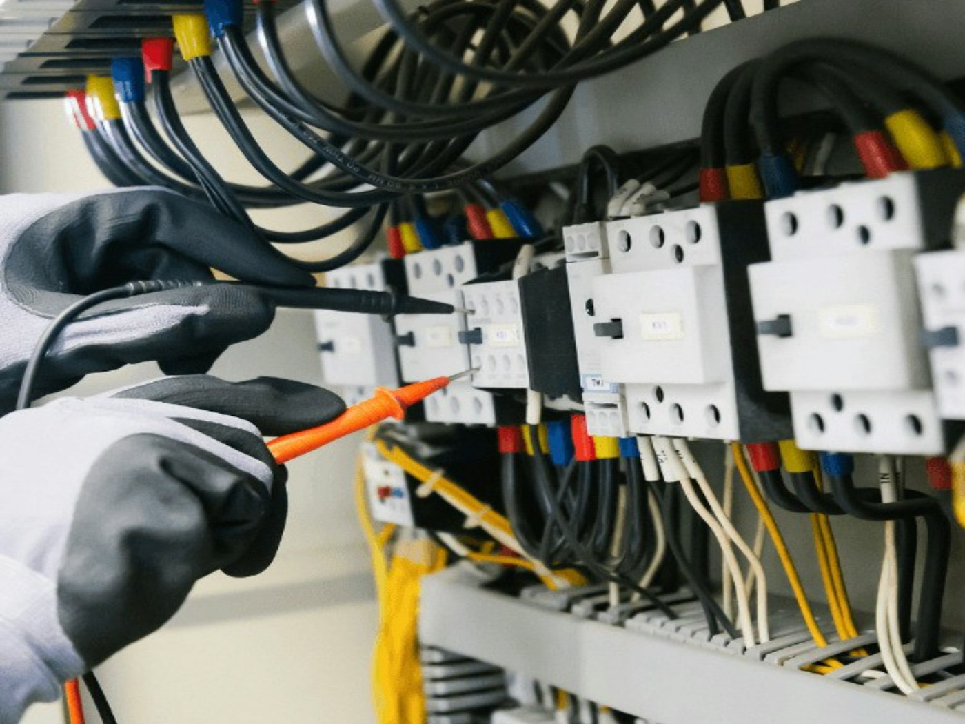 Electrician testing a live distribution panel with a digital multimeter
