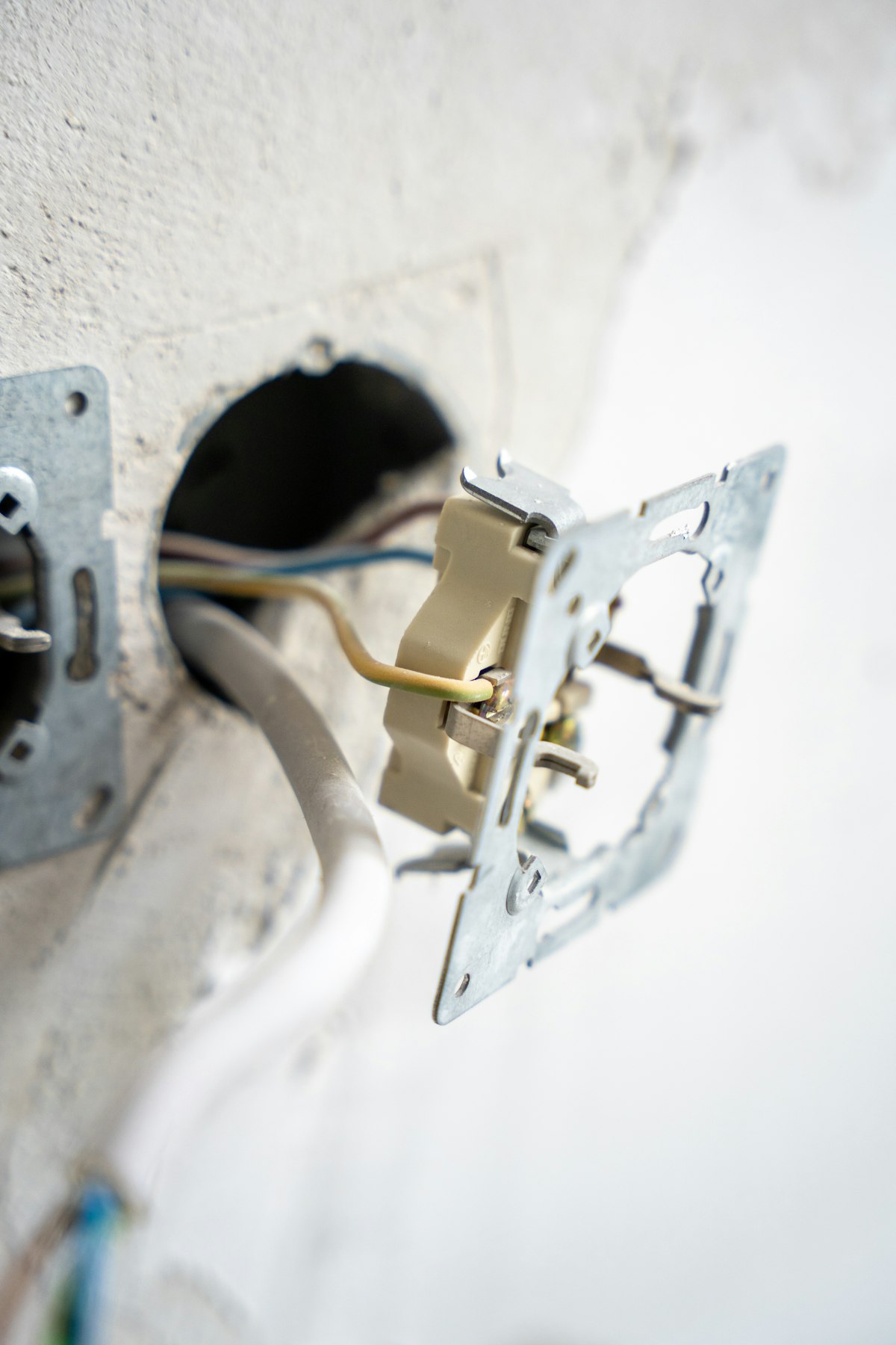 Exposed wiring and an open switch box on a wall during a rewiring job