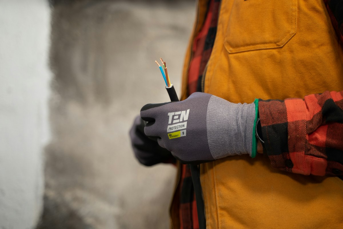 Gloved hands holding stripped electrical wires ready for a new appliance connection
